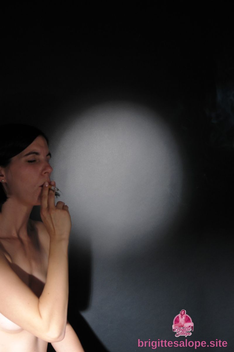 Femme en noir fumant dans l'obscurité — Brigitte la Salope