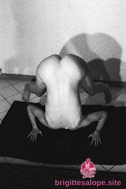 Musclé et nu, assis sur un tapis noir, lumière intense sur le dos — Brigitte la Salope